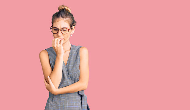 Beautiful caucasian woman with blonde hair wearing business clothes and glasses looking stressed and nervous with hands on mouth biting nails. anxiety problem.