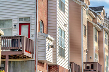 Fototapeta premium Townhouses exterior with balcony wooden siding and brick wall on a sunny day
