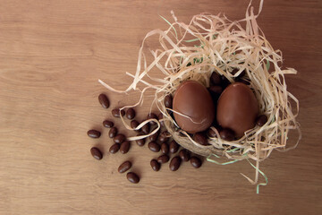 Chocolate Easter Eggs in wicker basket with candy on wooden background