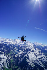 Naklejka na ściany i meble Skydiver performs stunts above snowcapped mountains