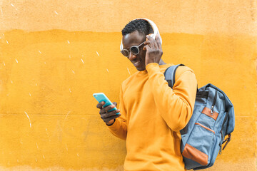 Black Man Listening Music Using Cellphone Wearing Yellow Sweater Outdoors.