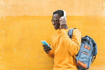Black Man Listening Music Using Cellphone Wearing Yellow Sweater Outdoors.