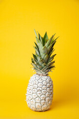 White pineapple on table in studio on yellow background