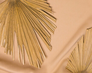 On the folds of the beige fabric are dry palm leaves. Natural and fashionable colors.Trend of the year.