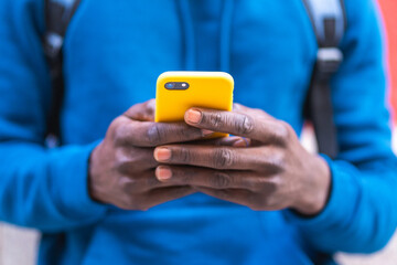 Close Up of Black Man Using Cellphone Wearing Blue Sweater Outdoors.