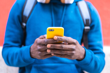 Close Up of Black Man Using Cellphone Wearing Blue Sweater Outdoors.
