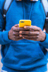 Close Up of Black Man Using Cellphone Wearing Blue Sweater Outdoors.