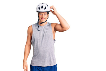 Young handsome man wearing bike helmet confuse and wonder about question. uncertain with doubt, thinking with hand on head. pensive concept.