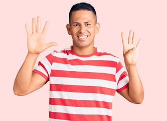 Naklejka premium Young handsome latin man wearing casual clothes showing and pointing up with fingers number nine while smiling confident and happy.