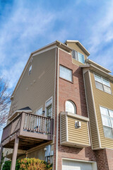 House with balcony and combination of brick and wooden siding at exterior wall