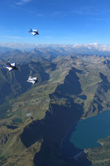 Wingsuit fliers glide in formation at sunrise