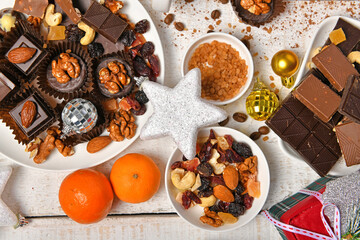 sweet food top view background for merry christmas or new year holiday decoration - chocolate candies, tangerines, cookies on white wood