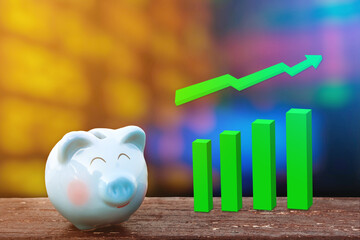 blue piggy bank on wooden table over chart of stock share over background chart business.