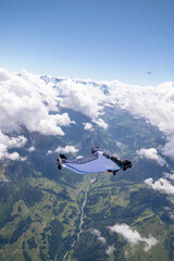 Fototapeta na wymiar Wingsuit flier glides high above land