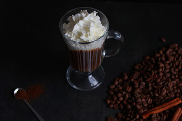 frothy coffee drink. Cappuccino or latte in a transparent glass on a dark background.