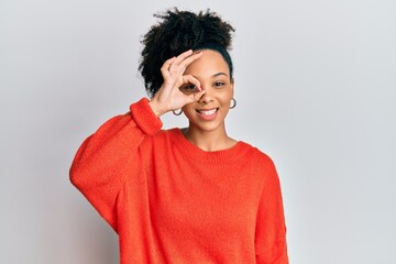 Young african american girl wearing casual clothes doing ok gesture with hand smiling, eye looking through fingers with happy face.