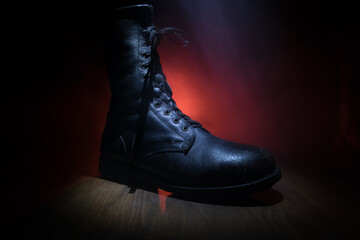 War concept. Old military shoe in a dark toned foggy background. Creative concept of conflict...