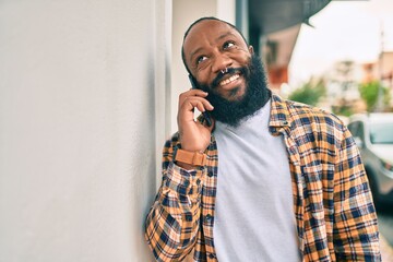 Handsome modern african american man with beard speaking on the phone at the city with a happy smile