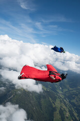 Tandem wingsuit fliers glide over mountains at sunrise