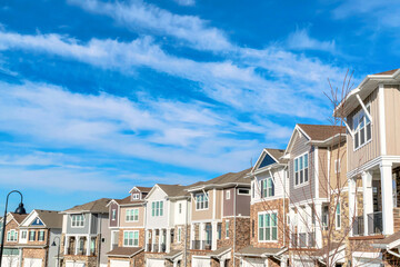 Peaceful neighborhood with row of multi storey homes set against cloudy blue sky