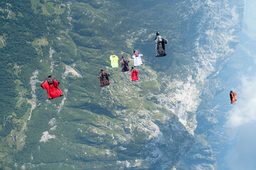 Team of wingsuit fliers glide in formation at sunset