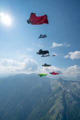 Team of wingsuit fliers glide in formation at sunset