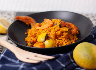 Plato negro de arroz en paella con langostinos y almejas.