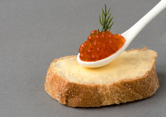 Red salmon caviar in a spoon with a sandwich