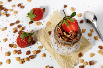 Natural yogurt with muesli and strawberries in a glass jar.