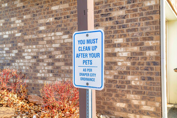 You Must Clean Up After Your Pets signage with brick wall of building background