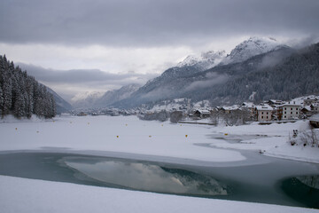 Fototapeta premium le nuvole sulla montagna in inverno, la luce che filtra le nuvole attorno una montagna innevata, lo splendido panorama invernale sulle dolomiti