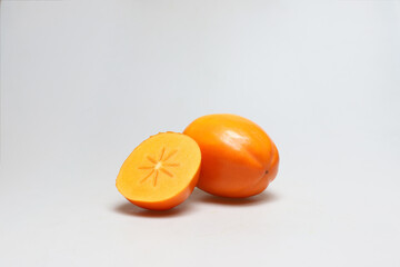 One whole and one half persimmon fruits next to each other on white background - portrait