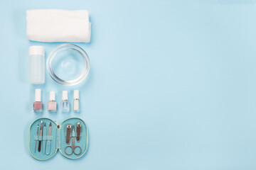Spa set equipment for manicure or pedicure with nail coat or polish, towel, water, on blue background, horizontal, copy space, top view
