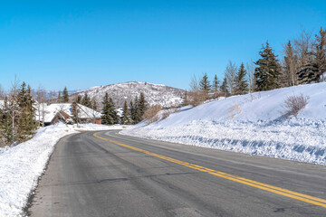 Obraz premium Park City landscape with paved mountain road on a scenic snowy scene in winter