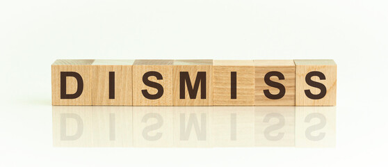 Wooden blocks with the text: dismiss. The text is written in black letters and is reflected in the mirror surface of the table.