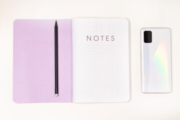 Notebook, pencil and modern smartphone on a white background.