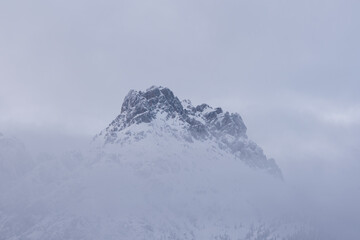 le nuvole sulla montagna in inverno, la luce che filtra le nuvole attorno una montagna innevata, lo splendido panorama invernale sulle dolomiti