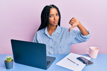 Beautiful hispanic woman working at the office with laptop with angry face, negative sign showing...