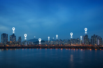 Fototapeta na wymiar Map pin icons on Seoul cityscape at dusk. Lit residential district and bridge along the Han River in Seoul, South Korea, at night. Copy space.