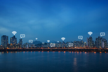 Lit residential district and bridge along the Han River in Seoul, South Korea, at night. Wireless network connection, WiFi, smart city and online messaging concept. Copy space.