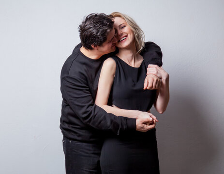 Caucasian heterosexual man and woman in black clothes on white background
