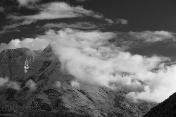 le nuvole sulla montagna in inverno, la luce che filtra le nuvole attorno una montagna innevata, lo splendido panorama invernale sulle dolomiti