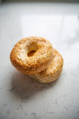 Bagels with sesame seeds on a marble kitchen counter, top view.