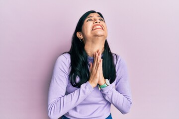 Young hispanic woman wearing casual clothes begging and praying with hands together with hope expression on face very emotional and worried. begging.