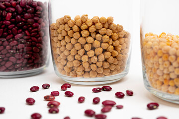 legumes. Chickpeas in a jar, red beans and peas out of focus in cans around the edges, sprinkling red beans partially out of focus