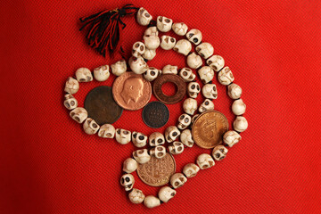 Vintage coins and rosary from India on red background