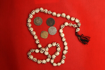 Vintage coins and rosary from India on red background