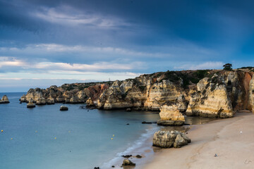 Fototapeta na wymiar Early morning on the Algarve coast. Famous rocks and calm ocean. Dramatic sky. Lagos, Portugal