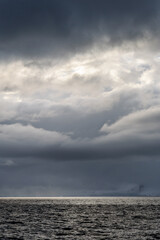 Stormy gray skies above the Southern Ocean with a sunbeam hitting the water, as a nature background 
