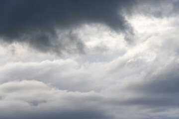 Stormy gray skies with some clouds highlighted white by the sun, as a nature background

